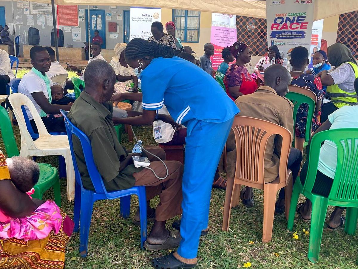 Health workers screen patients under a tent at a community health day